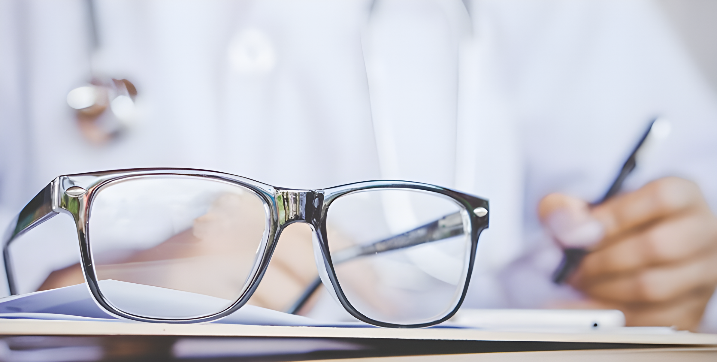 Occhiali da vista su una scrivania accanto a un medico che scrive