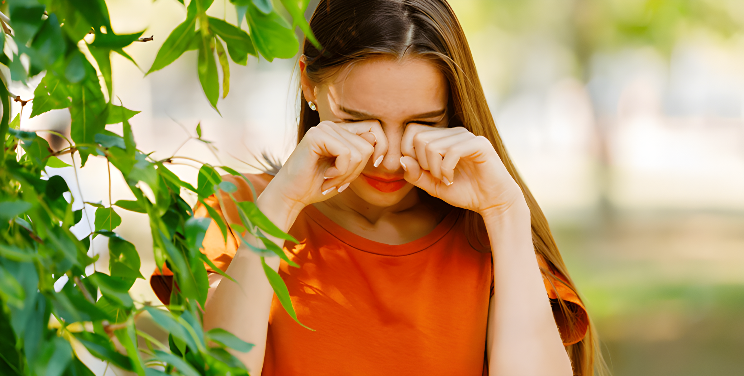Ragazza all'aperto tra il verde si strofina gli occhi arrossati per il prurito da allergia primaverile