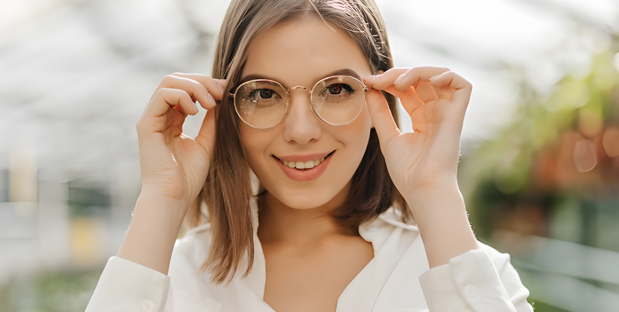 Giovane donna sorridente sistema i propri occhiali da vista all'aperto