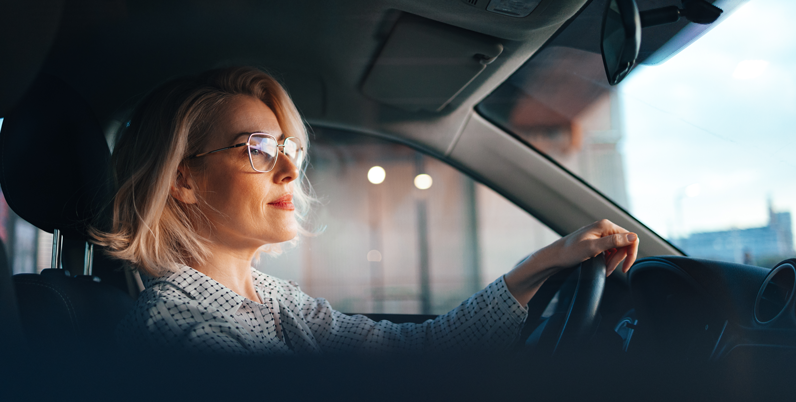 Donna bionda con occhiali da vista alla guida dell'auto