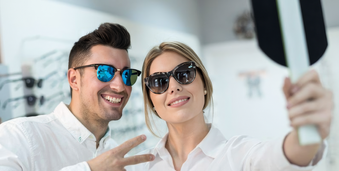 Coppia prova occhiali da sole davanti allo specchio in un negozio di ottica