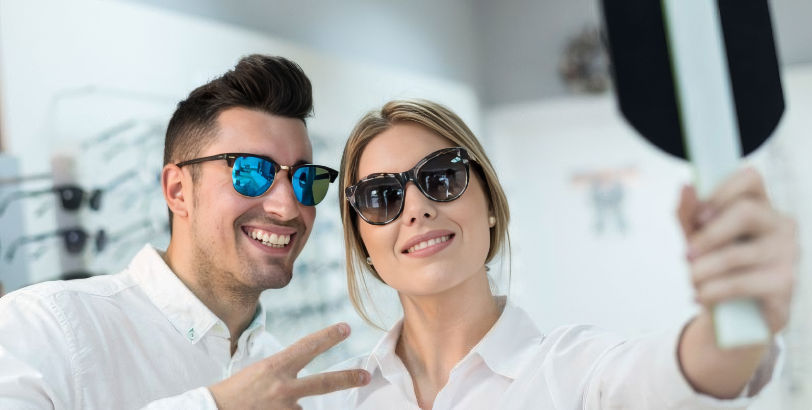Coppia prova occhiali da sole davanti allo specchio in un negozio di ottica
