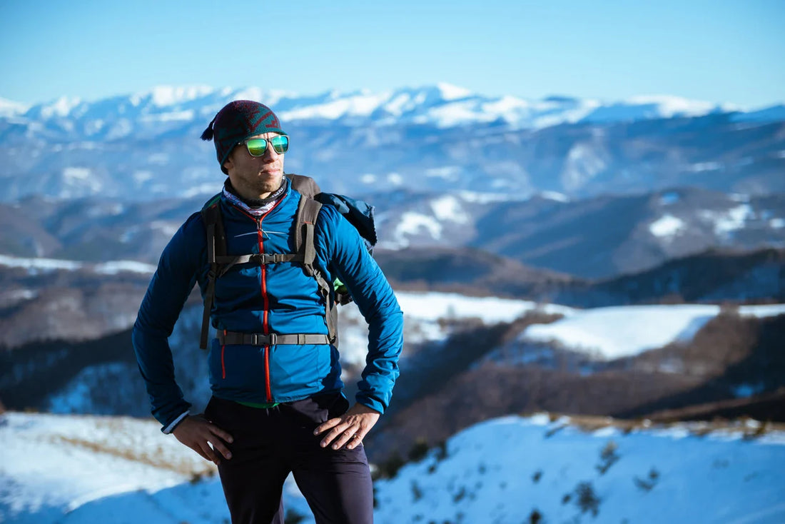 Escursionista in montagna innevata indossa occhiali sportivi avvolgenti