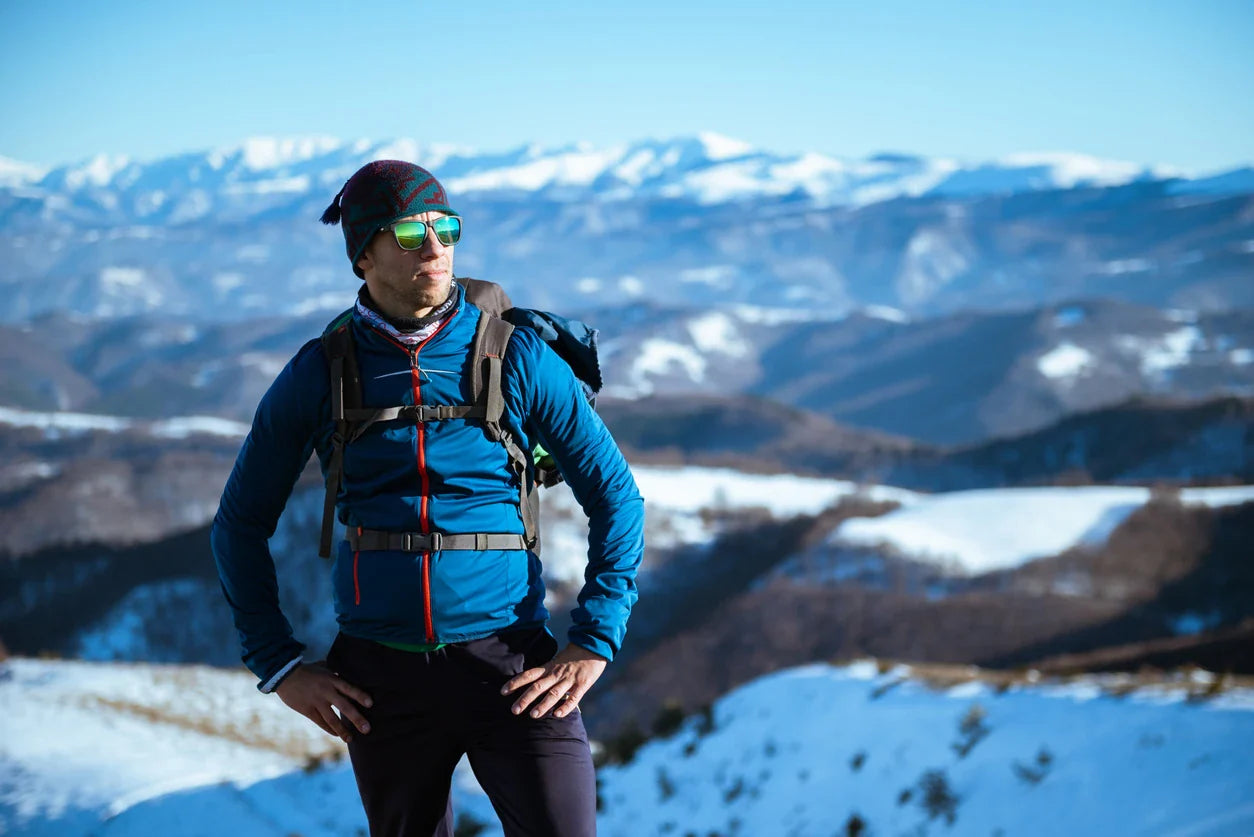 Escursionista in montagna innevata indossa occhiali sportivi avvolgenti