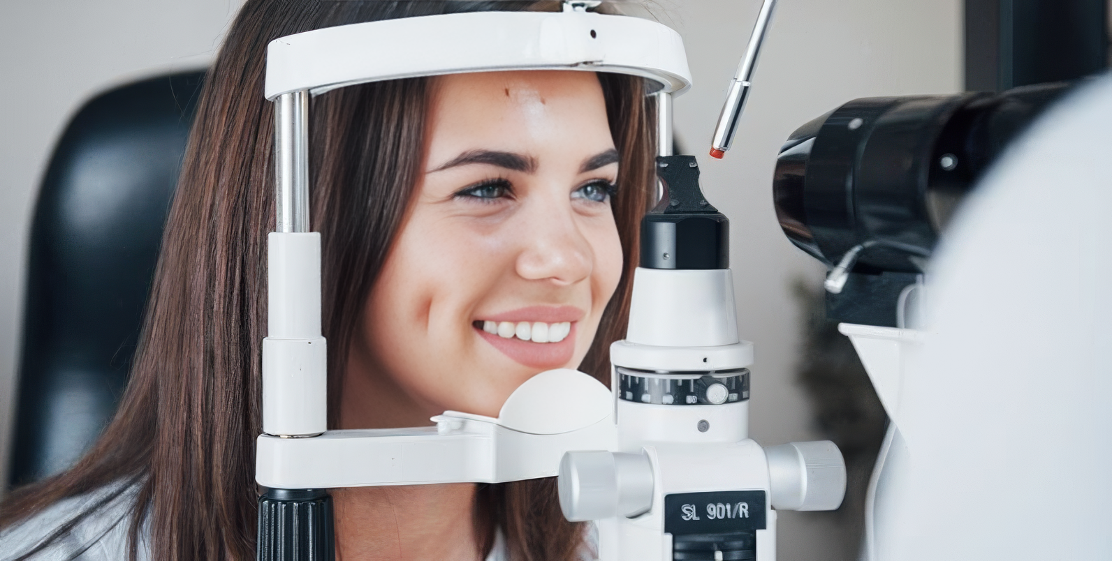 Giovane donna sorridente durante la misurazione della vista a uno strumento ottico
