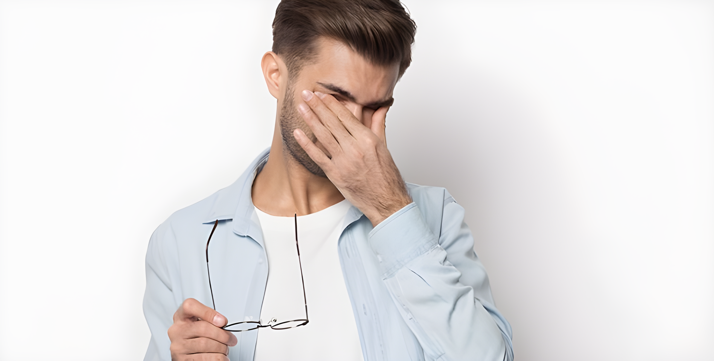 Uomo si copre l'occhio con la mano tenendo gli occhiali, fastidio da occhio secco