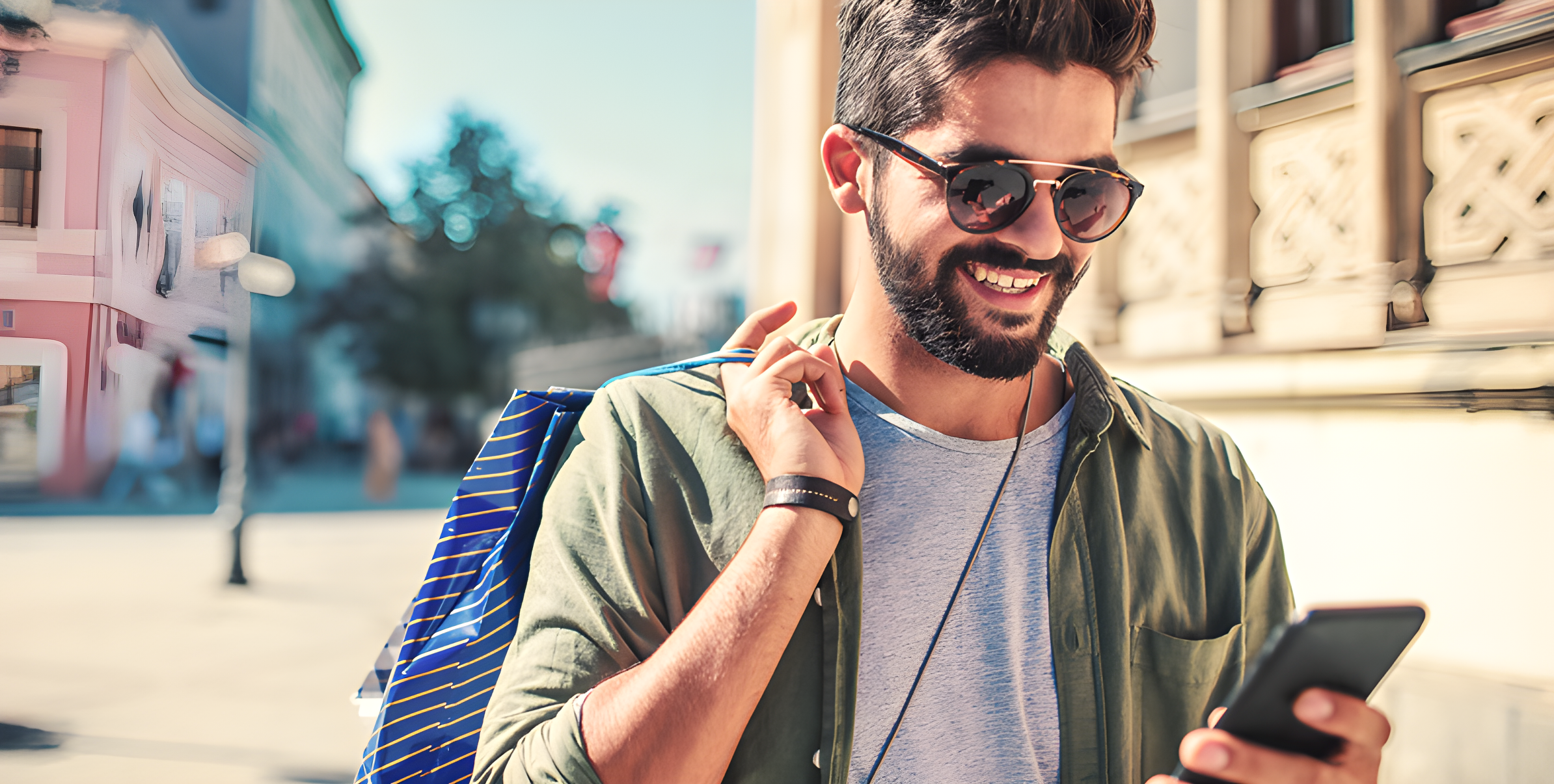 Uomo sorridente per strada con occhiali da sole, smartphone in mano, lenti che proteggono dai raggi UV
