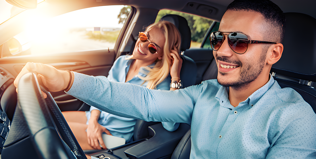 Uomo alla guida con occhiali da sole polarizzati e donna sorridente accanto