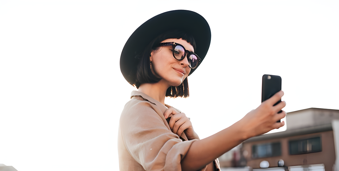 Donna con cappello e occhiali da sole si fa un selfie, le montature lanciate dagli influencer
