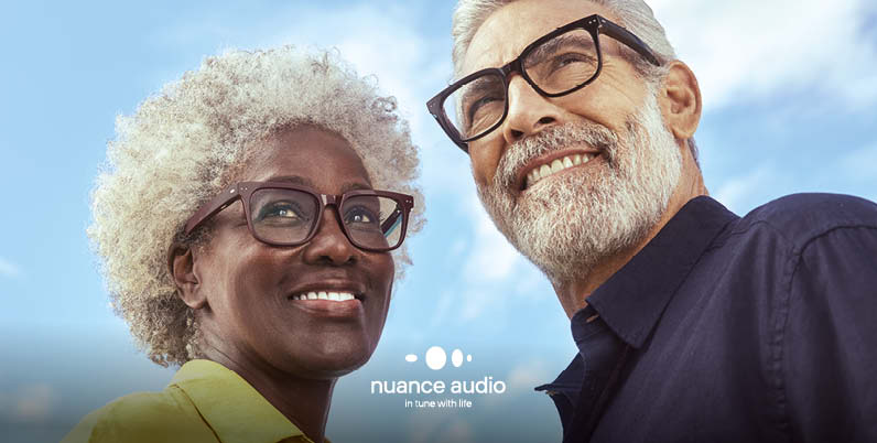 Coppia sorridente all'aperto indossa gli occhiali Nuance Audio che uniscono vista e udito