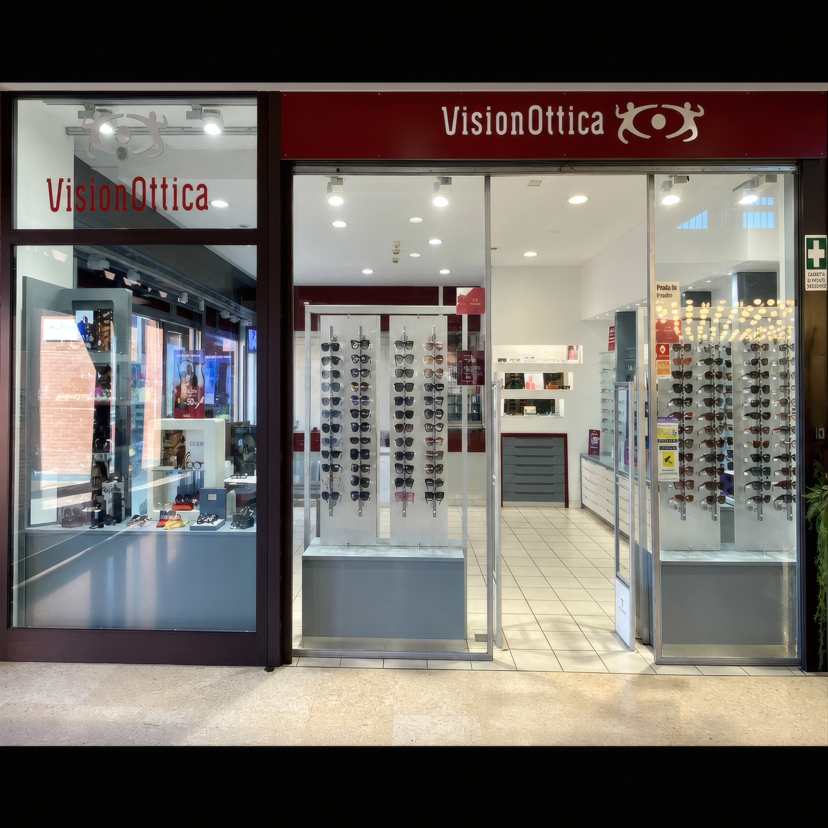 Interno del negozio VisionOttica del Centro Commerciale Campus di Parma con vetrina ampia affacciata sul corridoio del mall, espositori di montature visibili e insegna bordeaux VisionOttica in alto