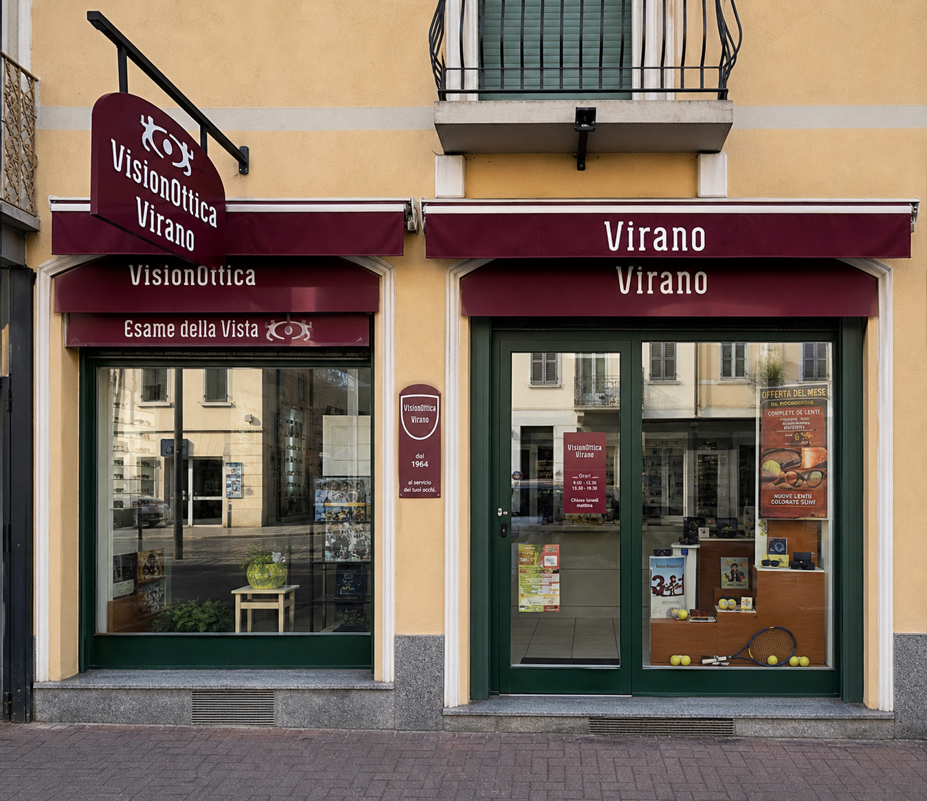 Facciata del negozio VisionOttica Virano di Orbassano su strada con doppia vetrina, insegna bordeaux, tenda a pensilina e insegna a bandiera laterale con logo