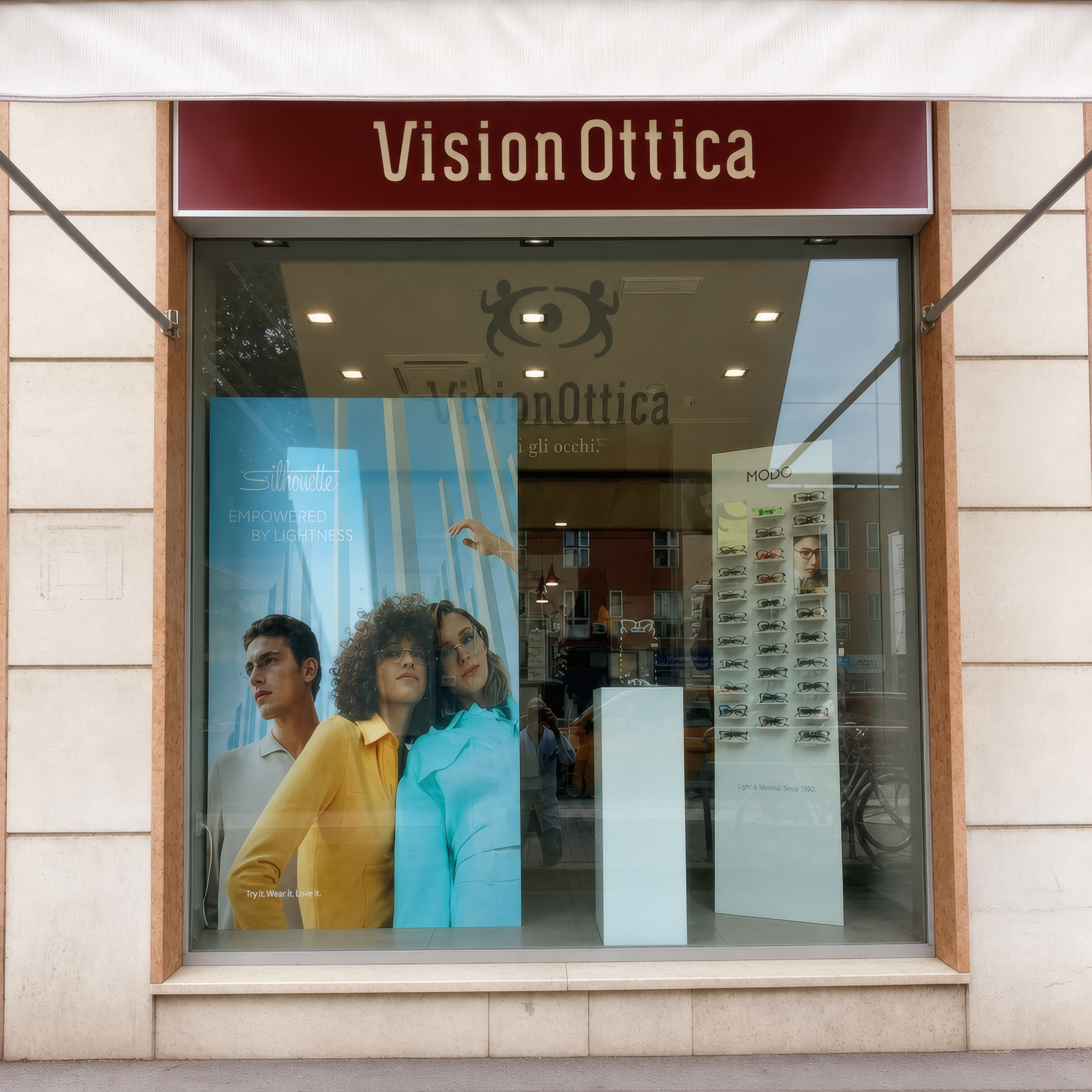 Vetrina del negozio VisionOttica Ripamonti di Milano su strada con insegna bordeaux, grande immagine fotografica con modelle e scaffali di occhiali visibili dall'interno