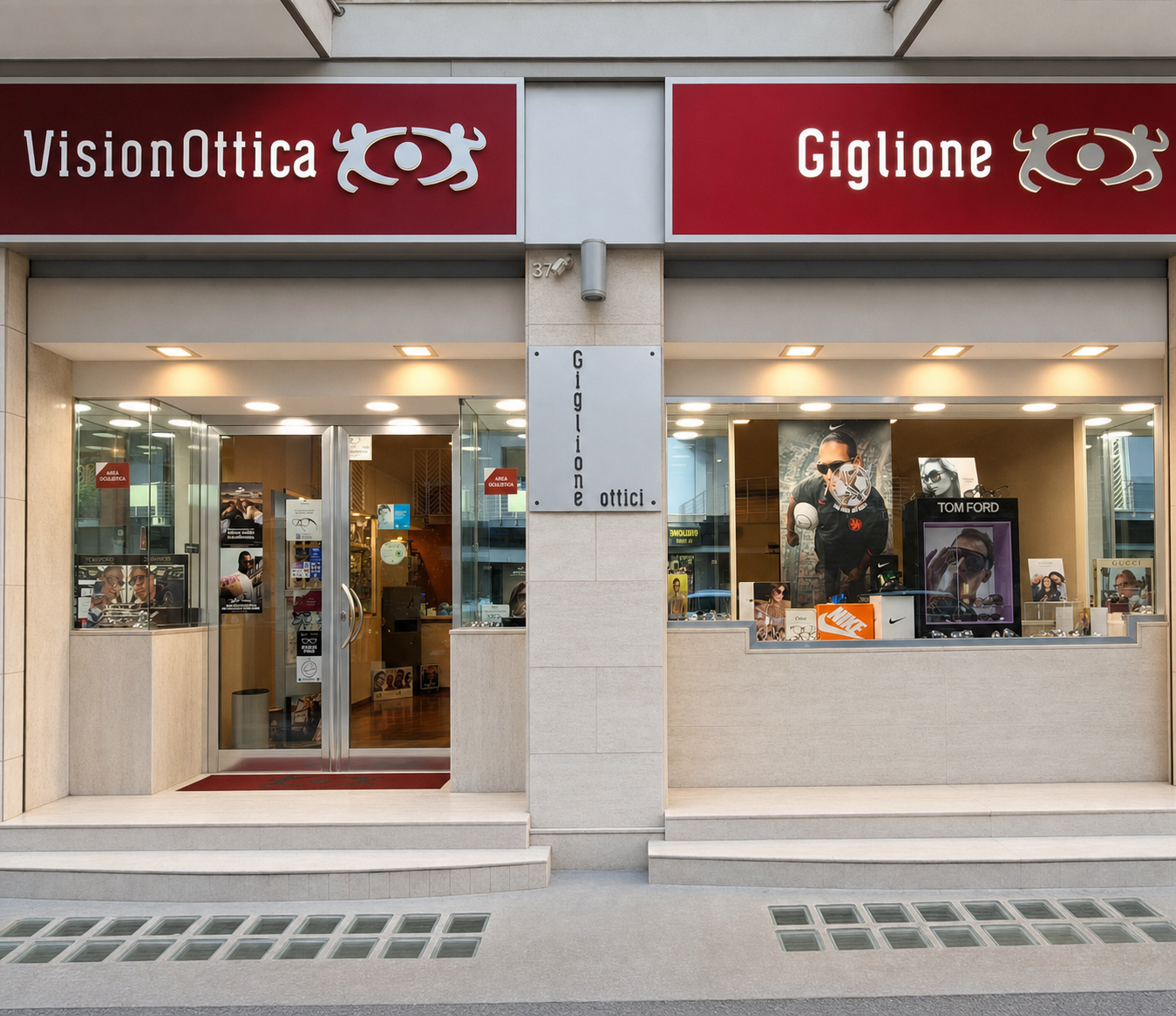Facciata del negozio VisionOttica Giglione di Bari su galleria coperta con doppia insegna rossa, porta aperta con tappeto rosso, vetrina con poster Tom Ford e banner fotografici