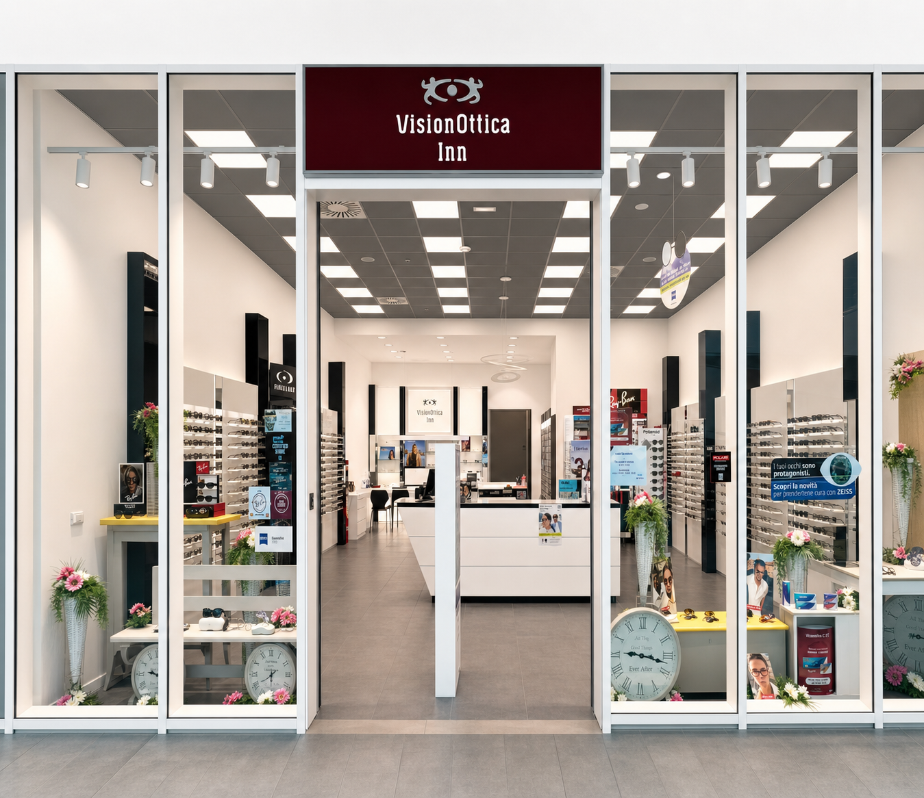 Ingresso del negozio VisionOttica Inn di Villa Verucchio in centro commerciale con insegna bordeaux, porta a vetri aperta e interno luminoso con espositori di occhiali su entrambi i lati