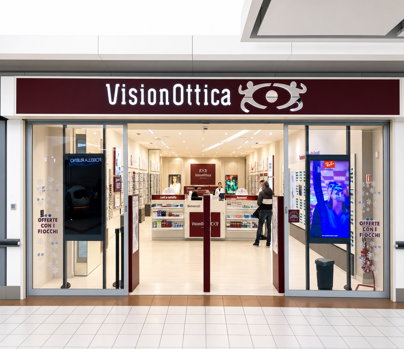 Ingresso del negozio VisionOttica Il Maestrale di Senigallia in centro commerciale con insegna bordeaux, porta scorrevole a vetri e interno con bancone centrale e espositori laterali