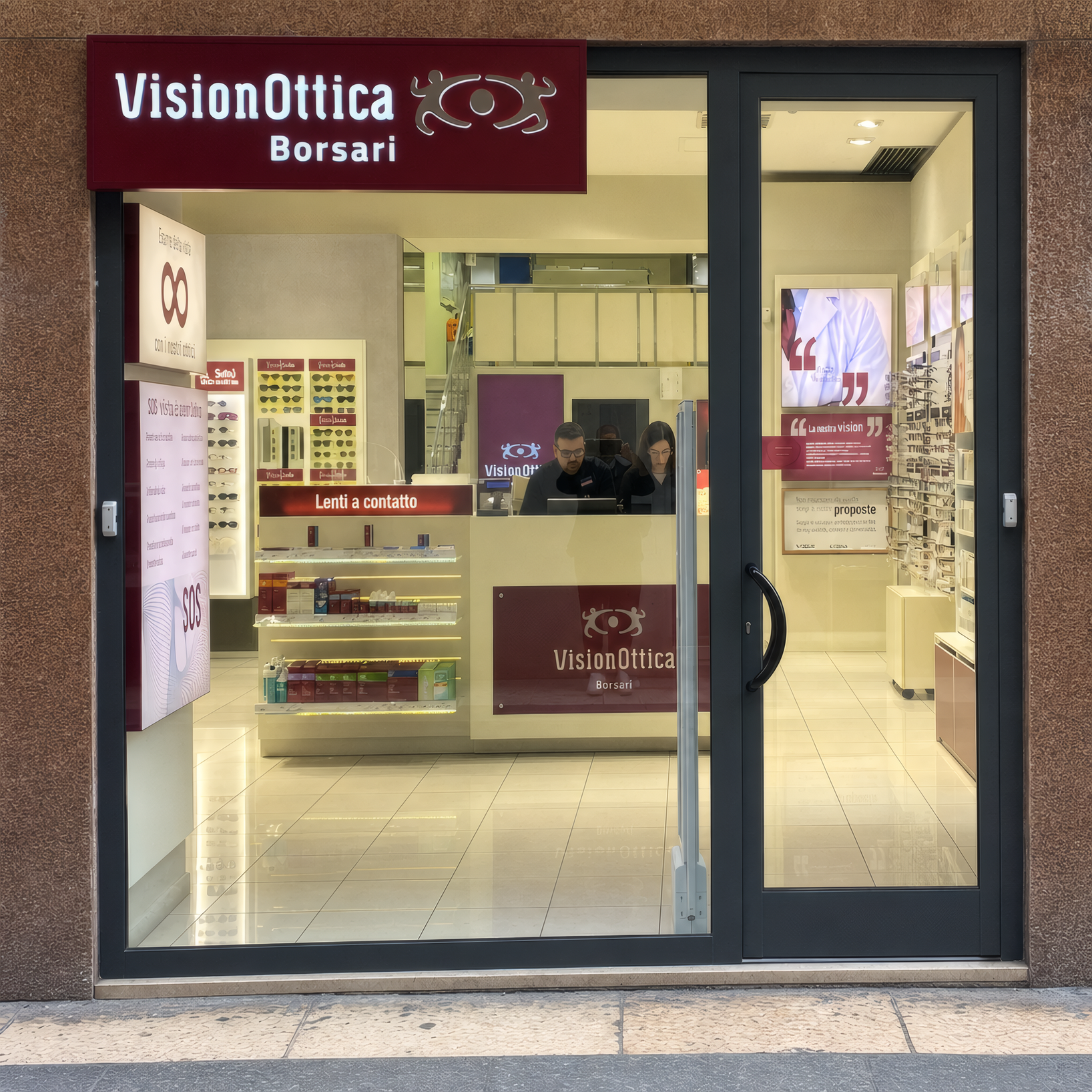 Facciata del negozio VisionOttica Borsari di Verona su strada con insegna bordeaux orizzontale, vetrina a tutta larghezza con vista sull'interno illuminato e bancone con operatori