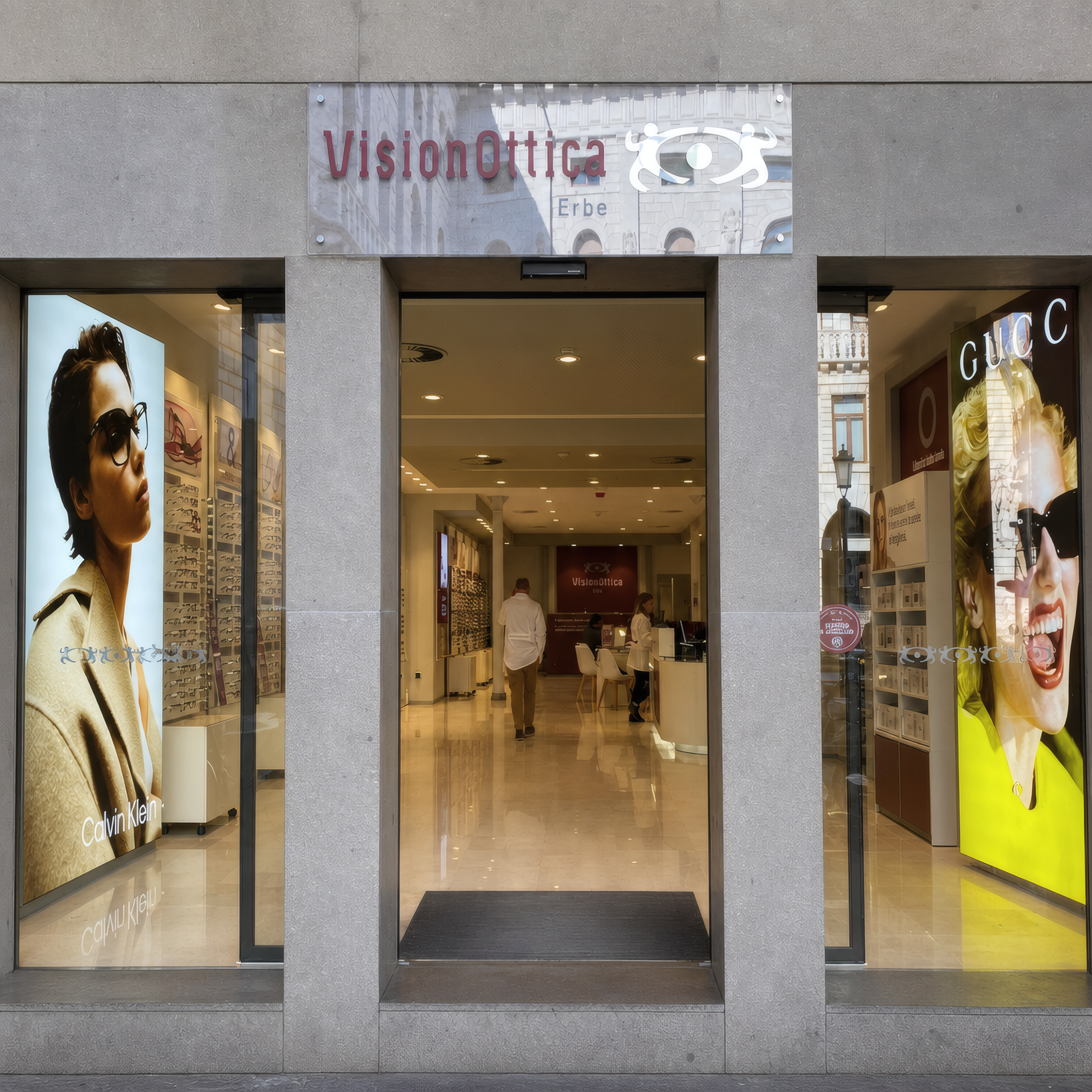 Facciata del negozio VisionOttica Erbe di Padova su strada in centro storico con insegna grigia, due vetrine illuminate con poster di moda e logo Gucci, porta centrale a vetri