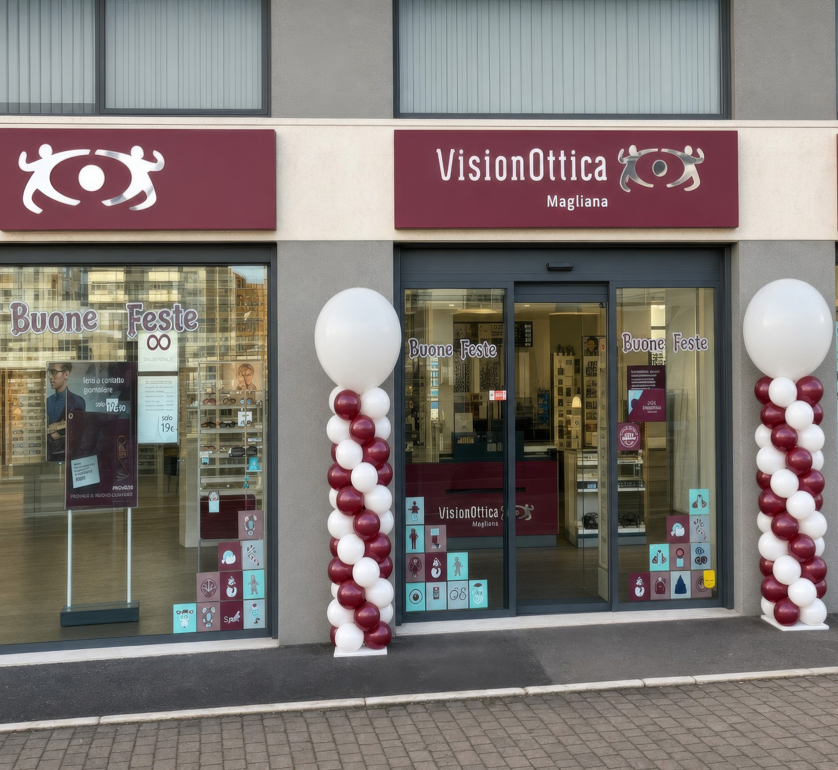 Facciata del negozio VisionOttica Magliana di Roma su strada con insegna bordeaux, porta a vetri automatica, decorazioni natalizie a palloncini e vetrine con allestimento Buone Feste
