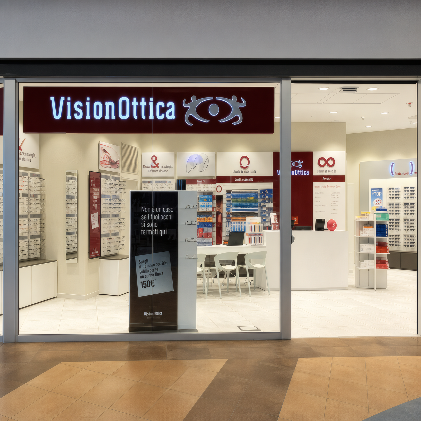 Ingresso del negozio VisionOttica Piazza Paradiso di Collegno in centro commerciale con insegna bordeaux, vetrina aperta e scaffali di occhiali visibili in profondità