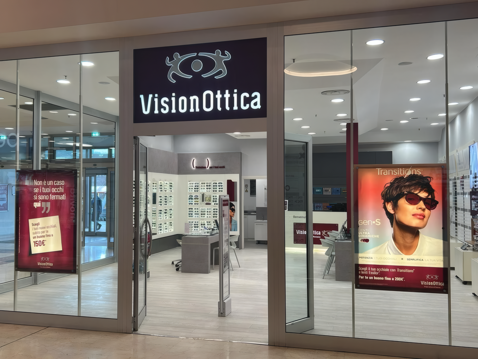 Ingresso del negozio VisionOttica Anzano di Anzano del Parco in centro commerciale con vetrina ampia, insegna nera e schermi promozionali laterali