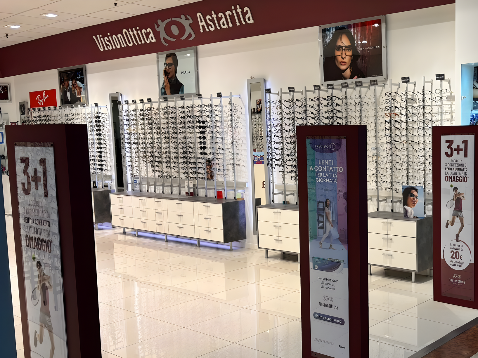 Interno del negozio VisionOttica Astarita di Novate Milanese in centro commerciale con pareti di espositori di montature e totem promozionali 3+1
