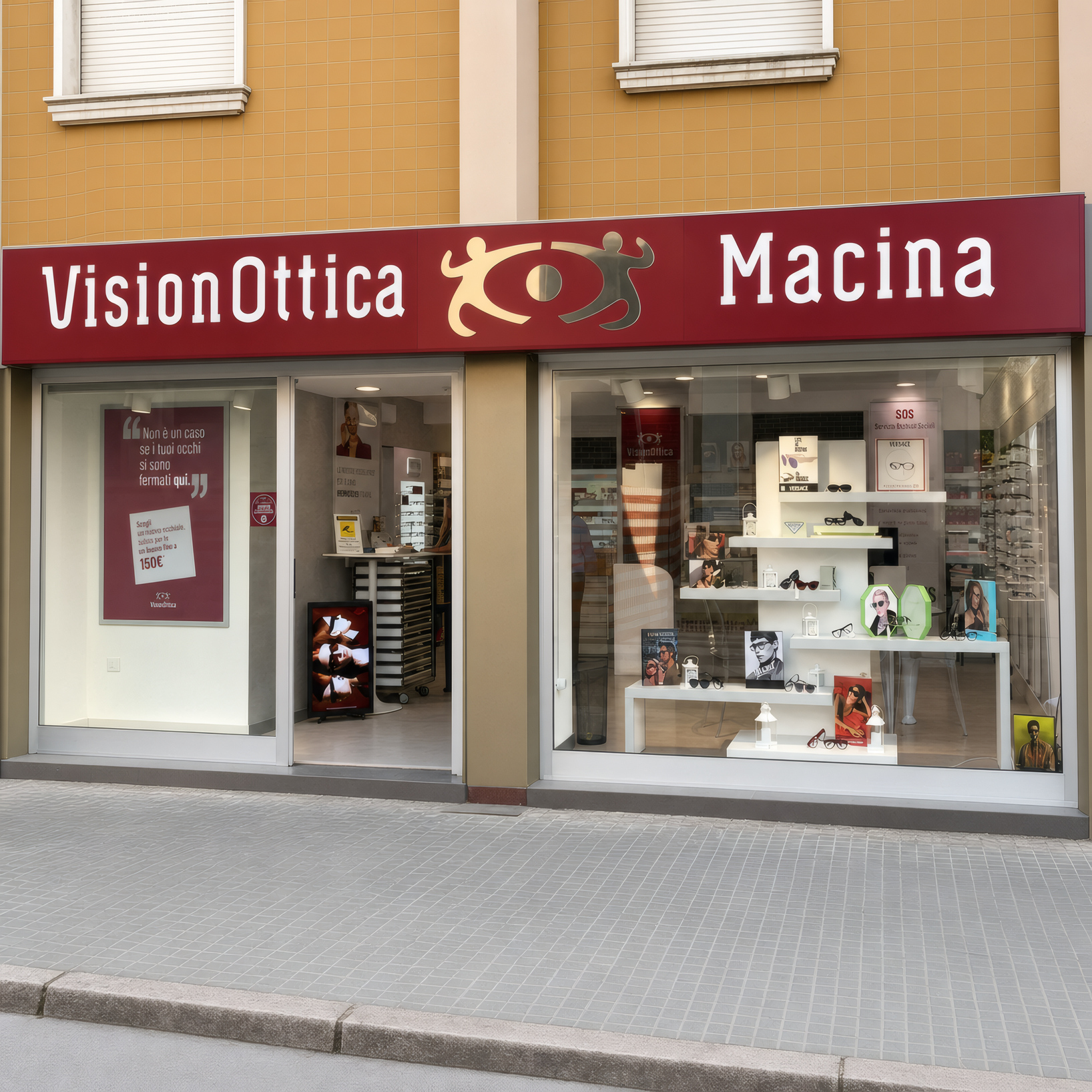 Facciata del negozio VisionOttica Macina di Sassari su strada con insegna bordeaux, vetrina con espositori di montature e accessori ottici