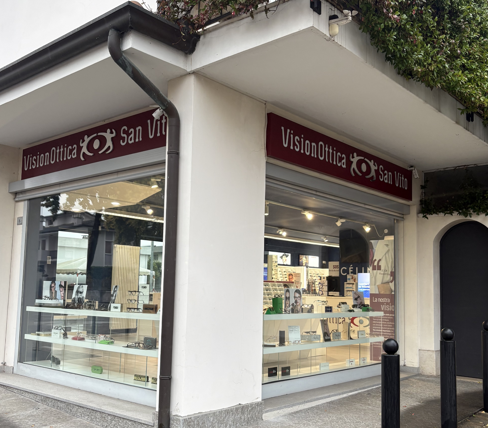 Facciata del negozio VisionOttica San Vito di San Vito al Tagliamento su via pedonale con doppia insegna bordeaux, due vetrine con montature e accessori esposti